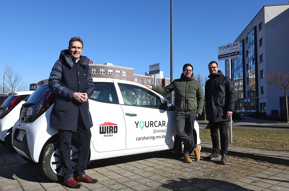 Ralf Zimlich, Vorsitzender der WIRO-Geschäftsführung, übernimmt ein Yourcar-Auto von Adrian Merker und Jakob Richter.